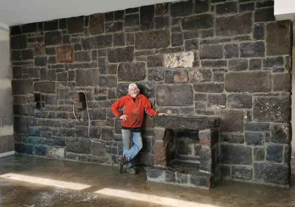 Master stonemason Gerry Shearer standing in front of an internal bluestone wall