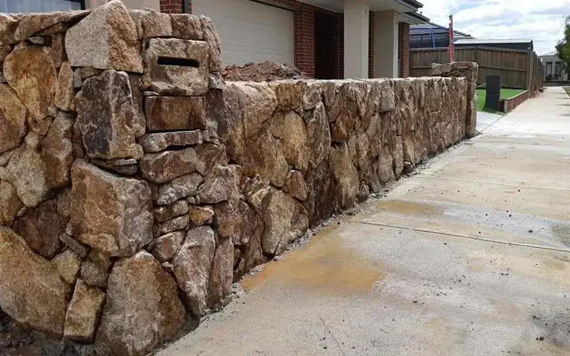 Large rock wall beside a driveway